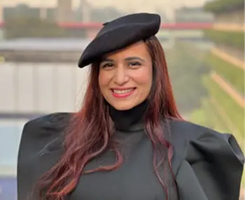 Woman in a black outfit and beret smiling outdoors