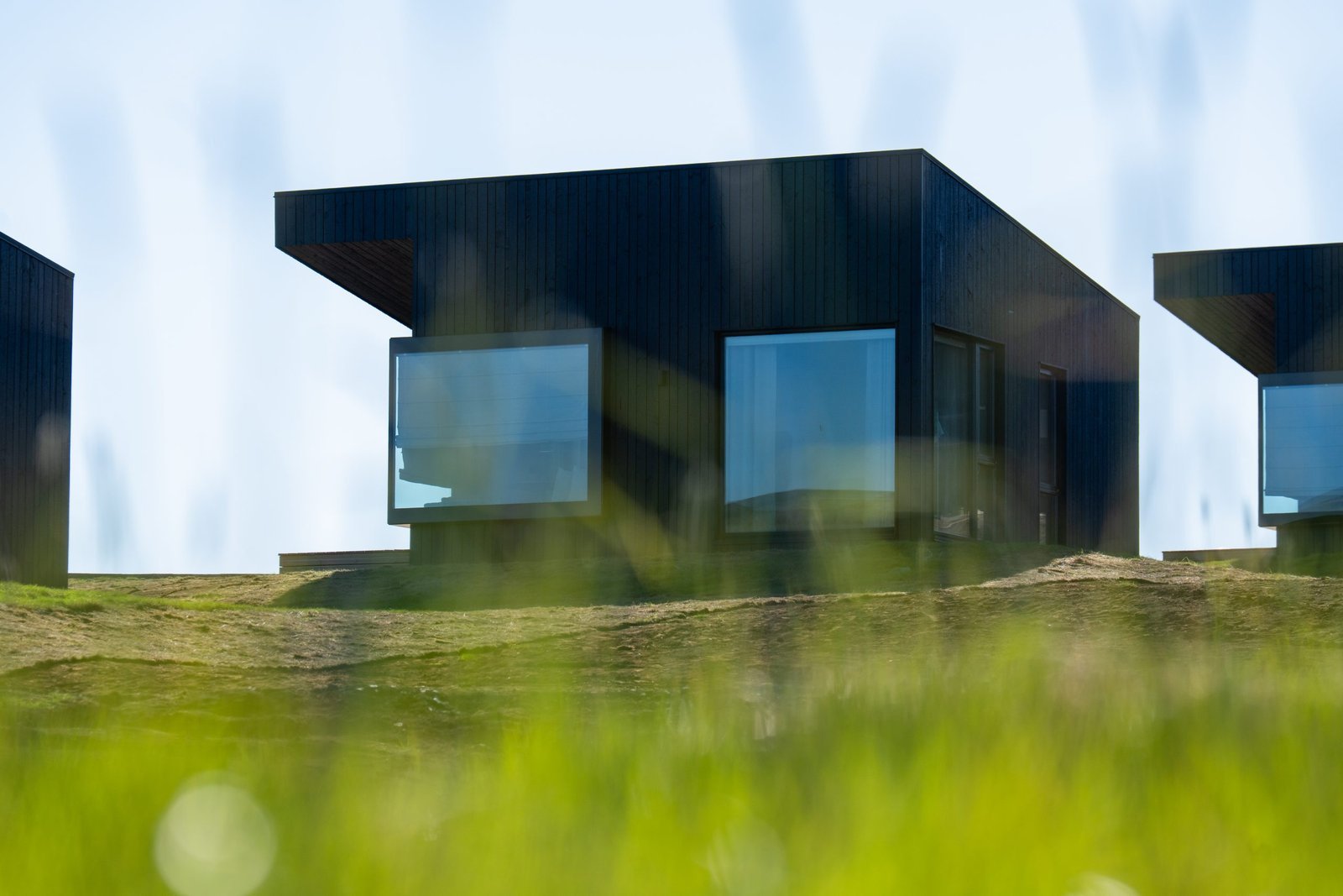 Black building with grass in the front at Peninsula Suites Iceland