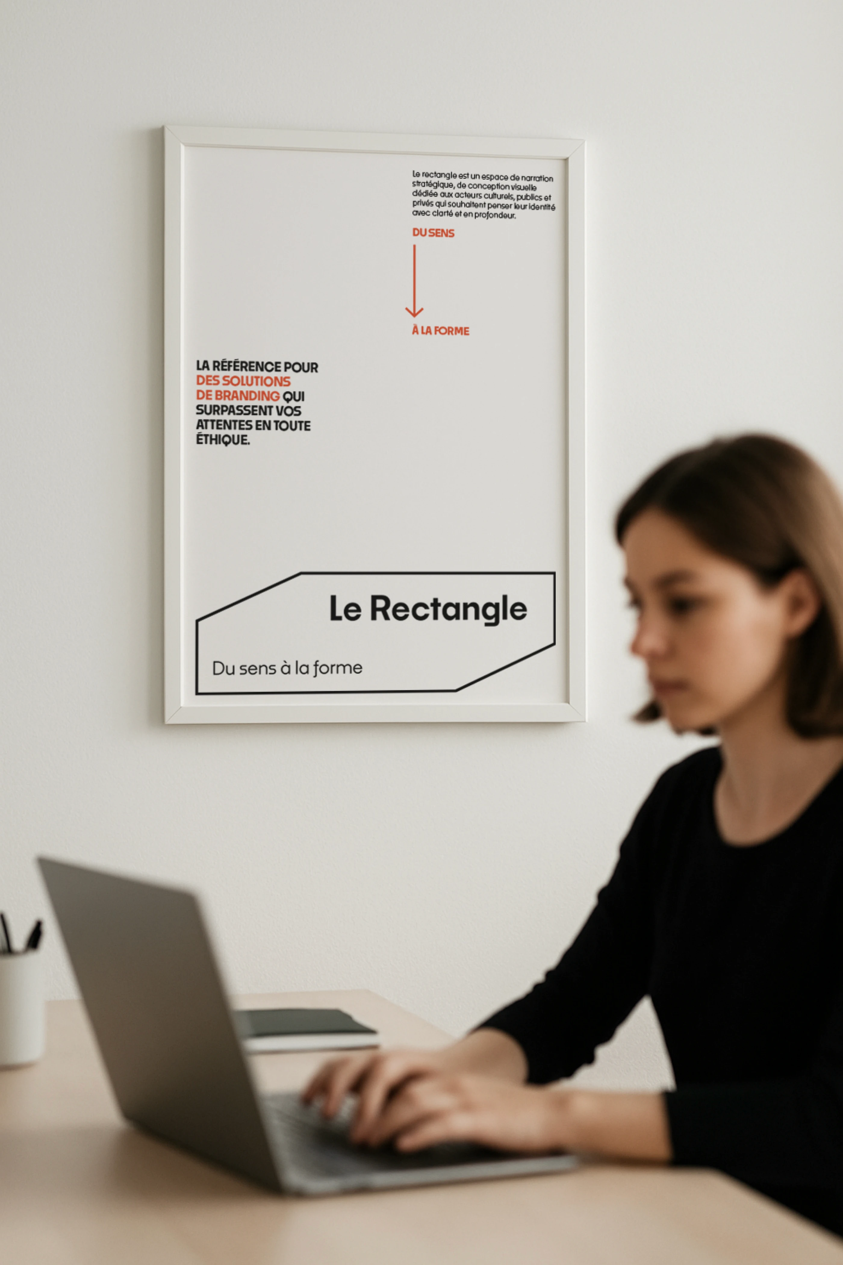 Affiche de la charte graphique Le Rectangle encadrée au mur au-dessus d'un poste de travail moderne.