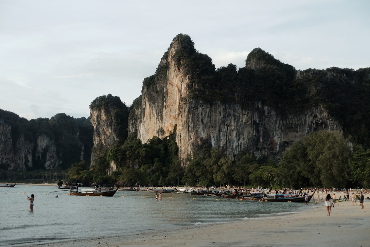 Longtail boats below limestone cliffs in Krabi, the postcard side of the Bali vs Thailand beach debate
