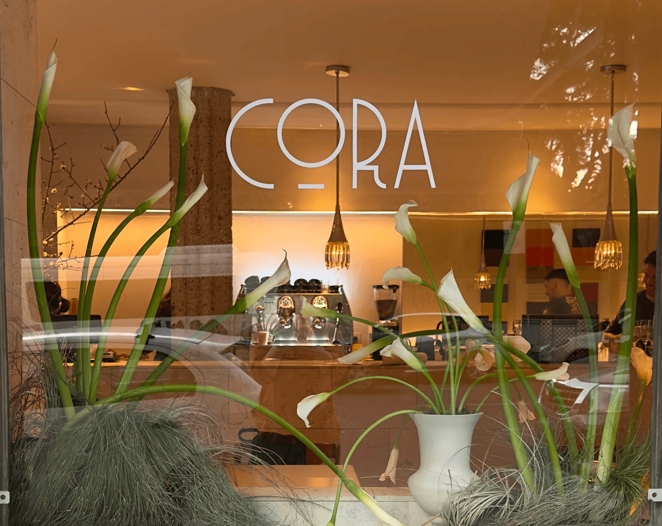 Vidriera del café Cora con arreglo de calas blancas.