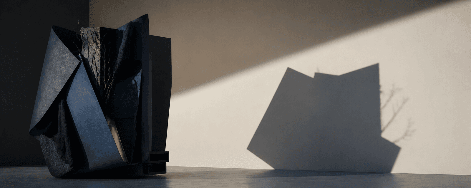 A complex navy and cobalt sculpture casts a simplified shadow on an ivory wall.