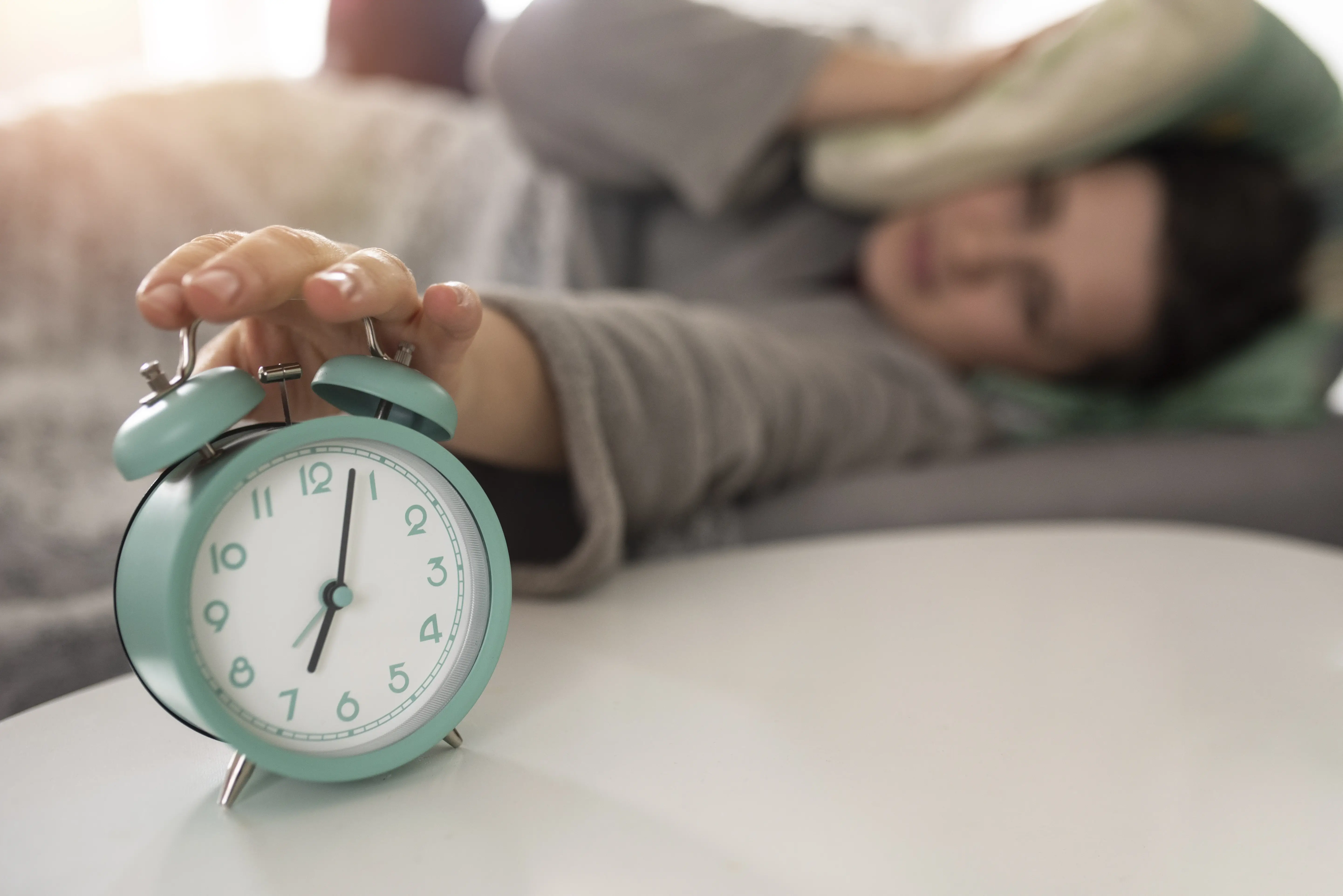 Persona tratando de apagar la alarma despertador en medio de la noche, reflejando dificultades para dormir