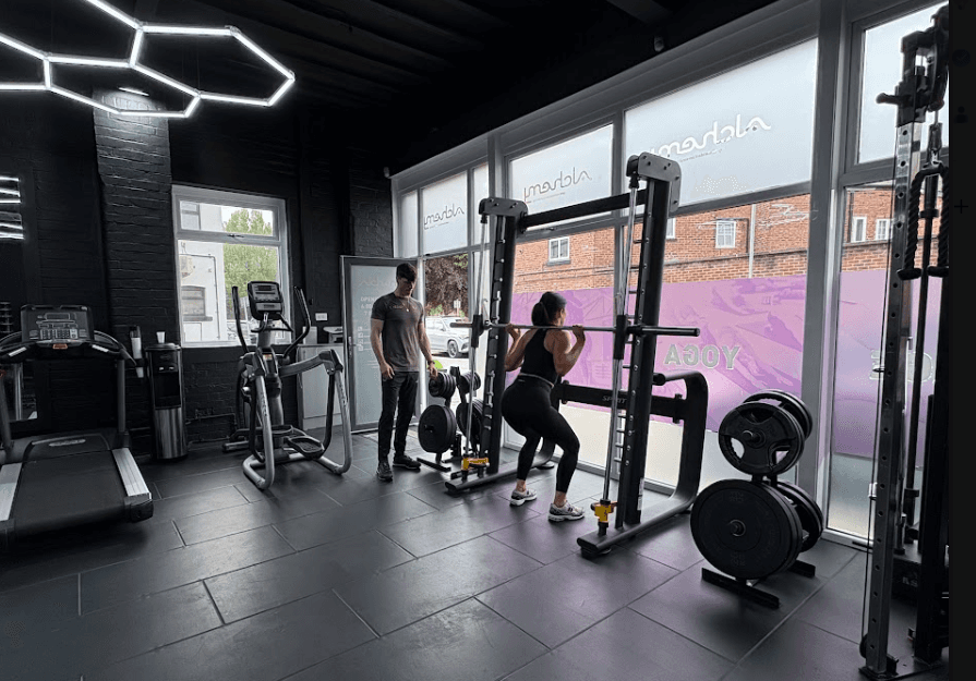 Personal trainer in Wilsmlow guiding a client with a strength training exercise. 