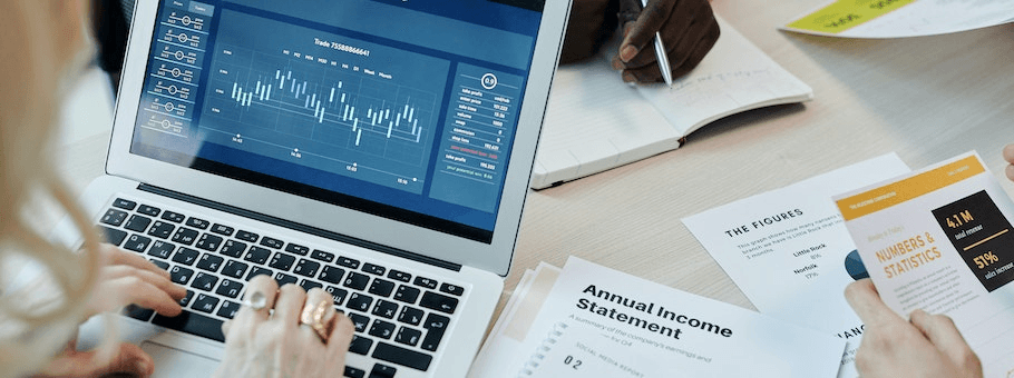 High school student writing a research hypothesis at a desk with academic journals and a laptop
