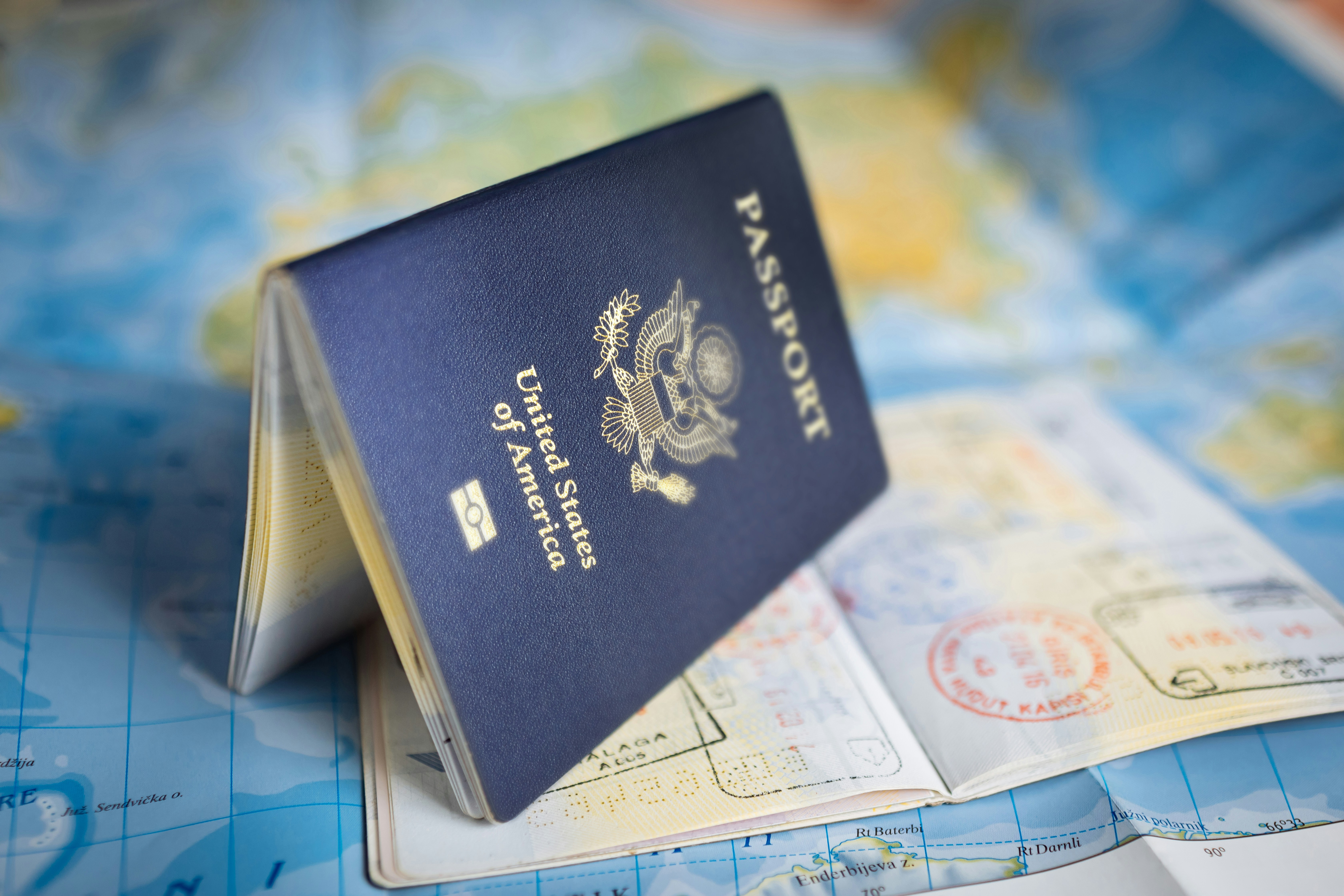 US passport on a world map with stamped pages, preparing child travel consent paperwork