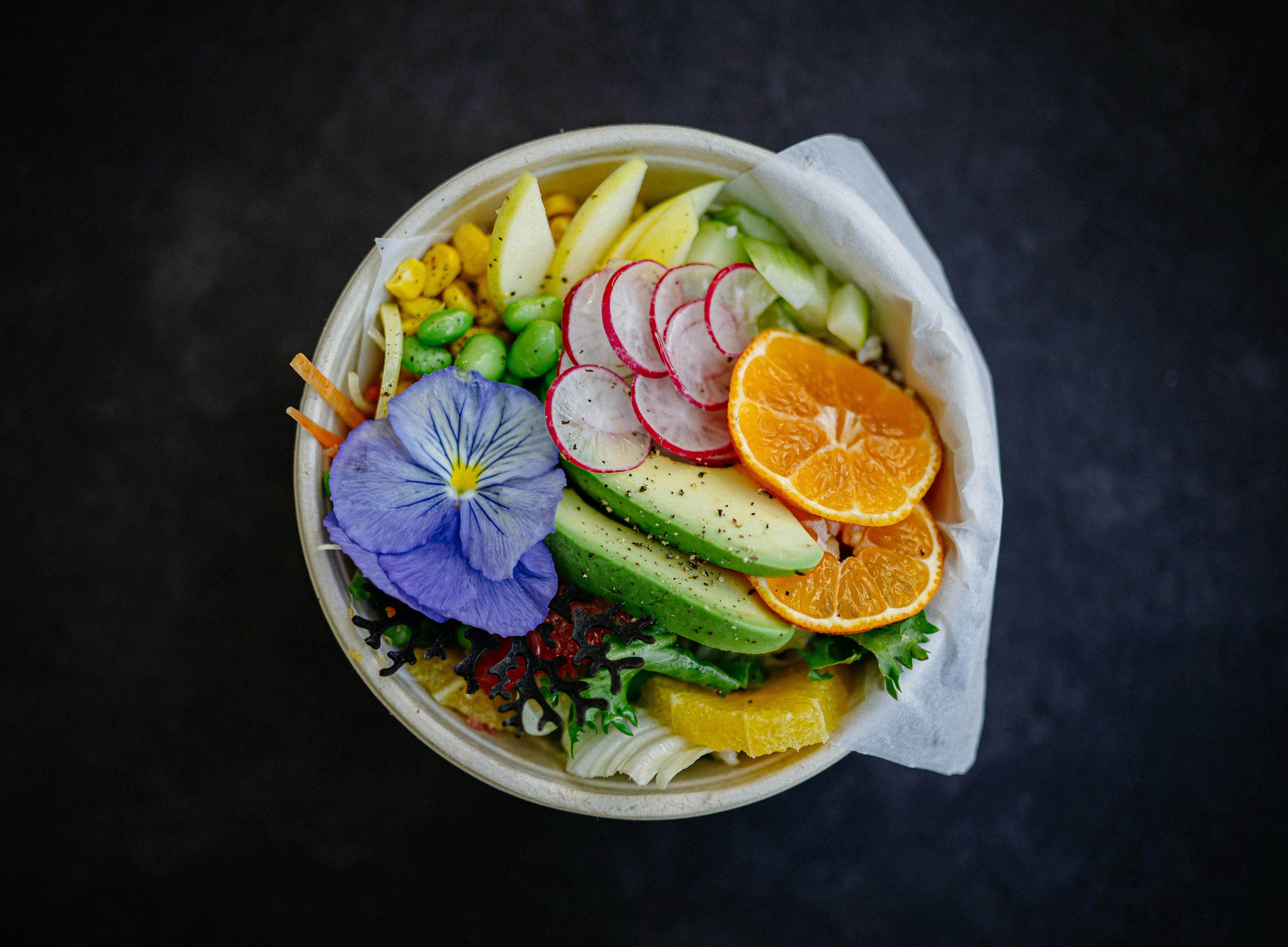 A balanced bowl with avocado, chickpeas, cherry tomatoes, roasted sweet potato, and leafy greens, showing a colorful plate built around allergen-free foods