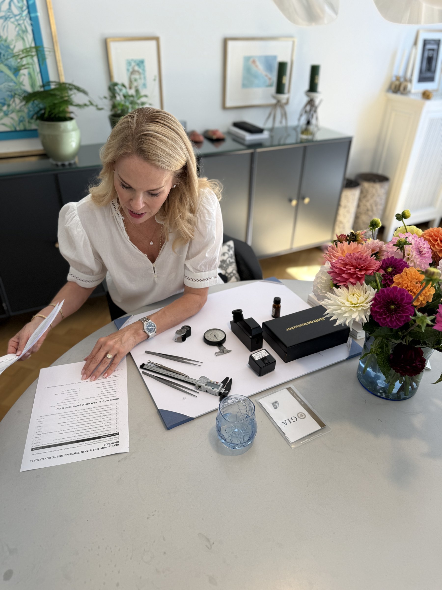Diamond advisor reviewing a grading report at a table with diamond tools and flowers