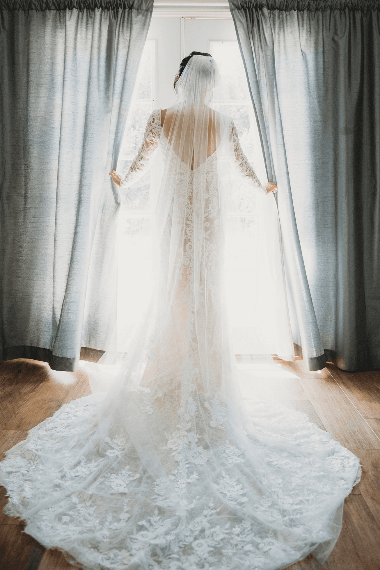 Bride opening curtains at double doors with sunlight streaming in