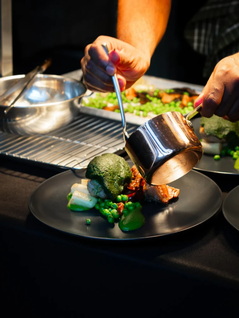Finishing a lamb main with sauce from a copper saucepan