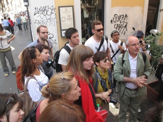 A group of people standing in the street and looking at something.