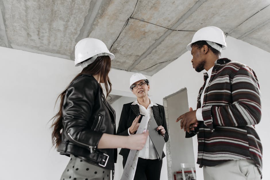 A diverse group of construction professionals wearing hard hats in a discussion at a building site.