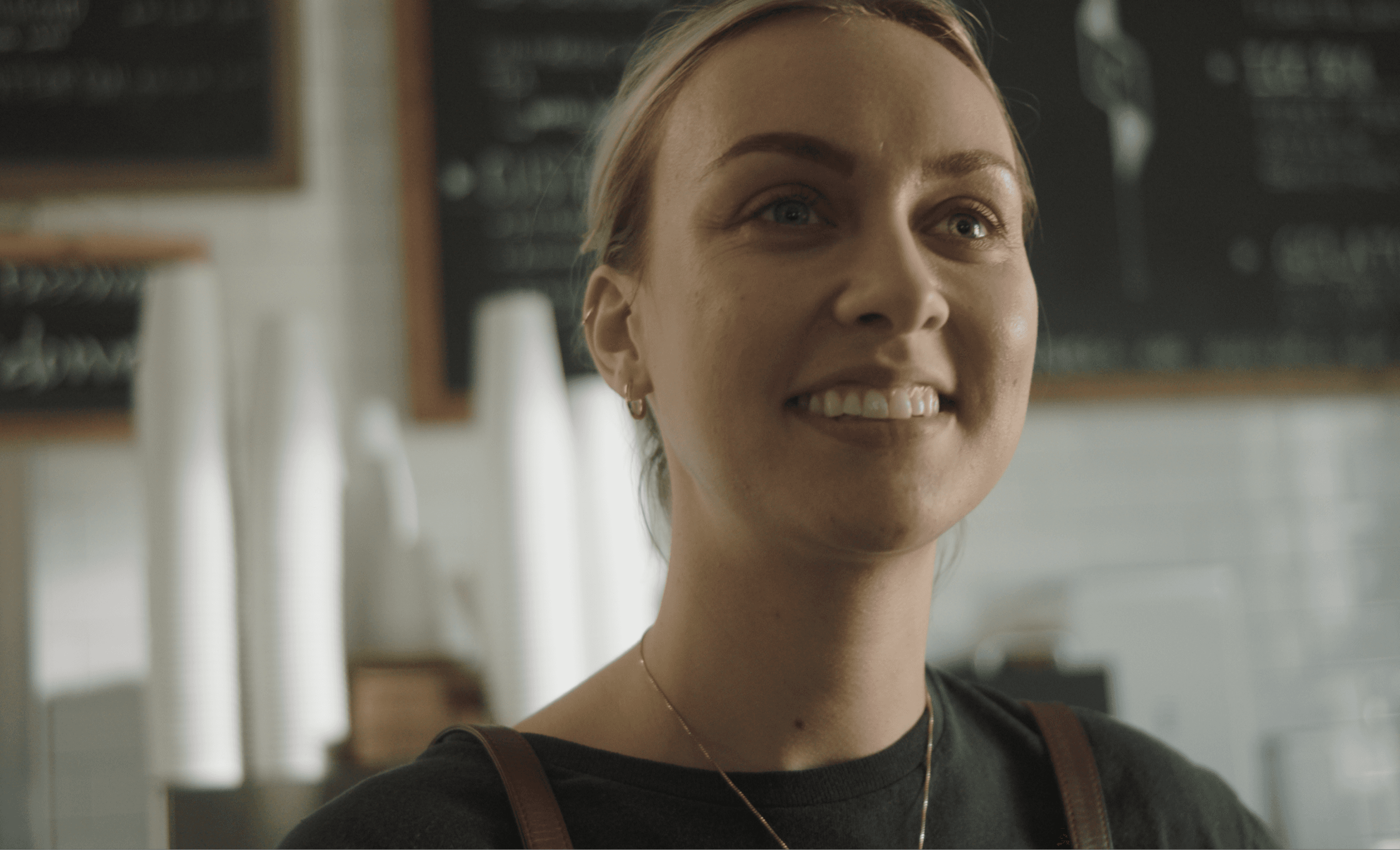 Woman in a café apron smiling warmly