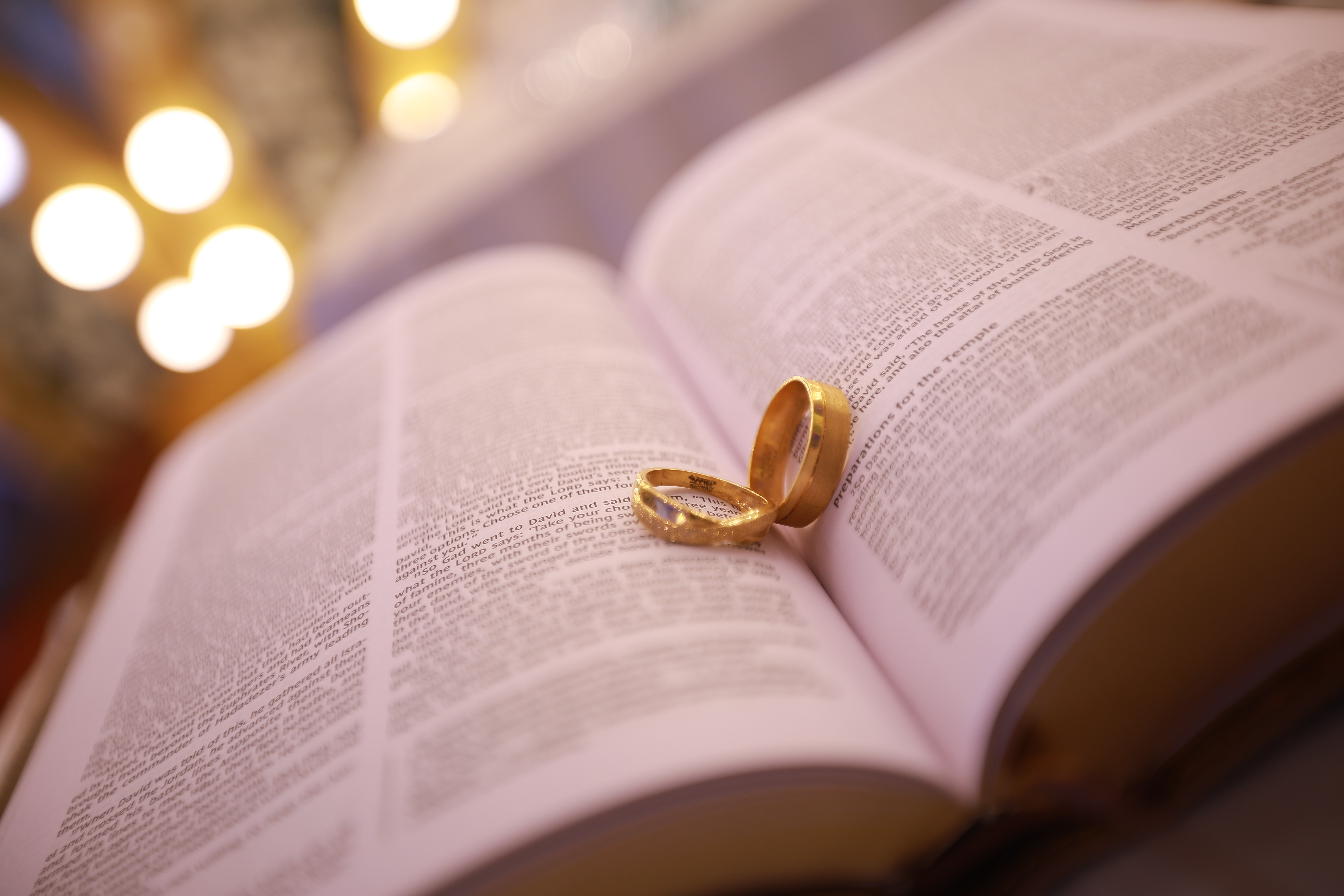 Two gold wedding rings rest atop a soft, textured fabric with a subtle pattern. The rings shine under gentle light, evoking themes of love and commitment.