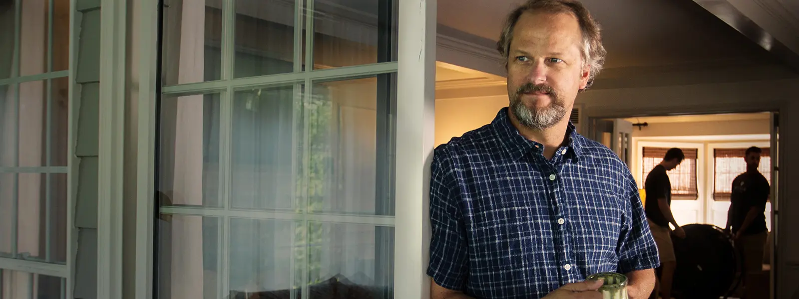 An senior gentleman standing thoughtfully in a home, representing compassionate senior relocation and transition services.