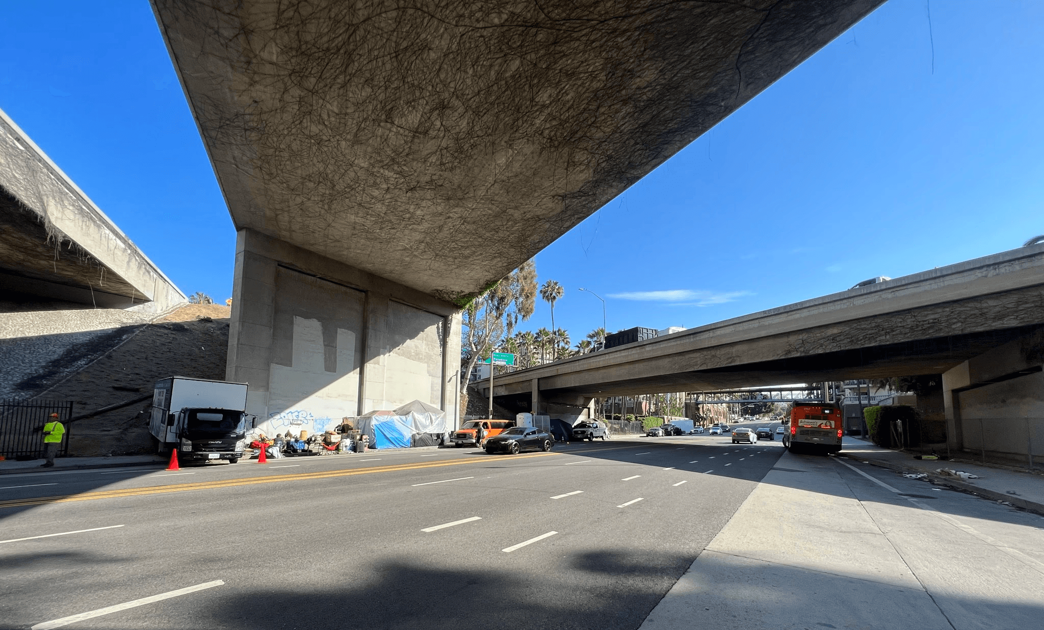 Street view under a highway crossing with blue skye in the background.