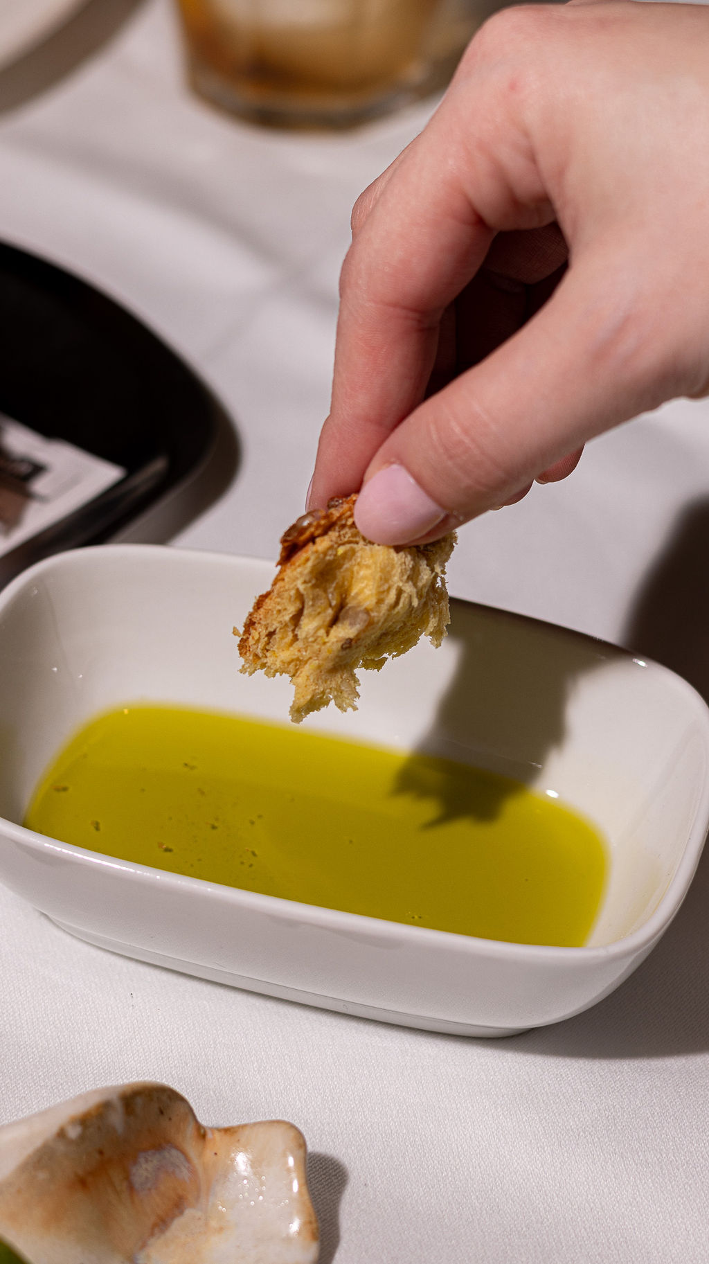 Restaurant interior with wooden tables and chairs lined against a textured wall, softly lit by round wall lamps.