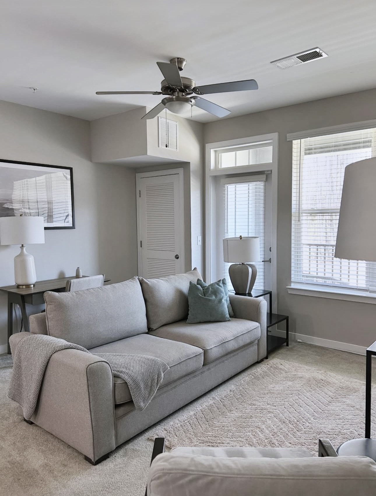 Professionally cleaned Airbnb living room with vacuumed carpets, staged pillows, and a tidy desk area for rental turnover services.