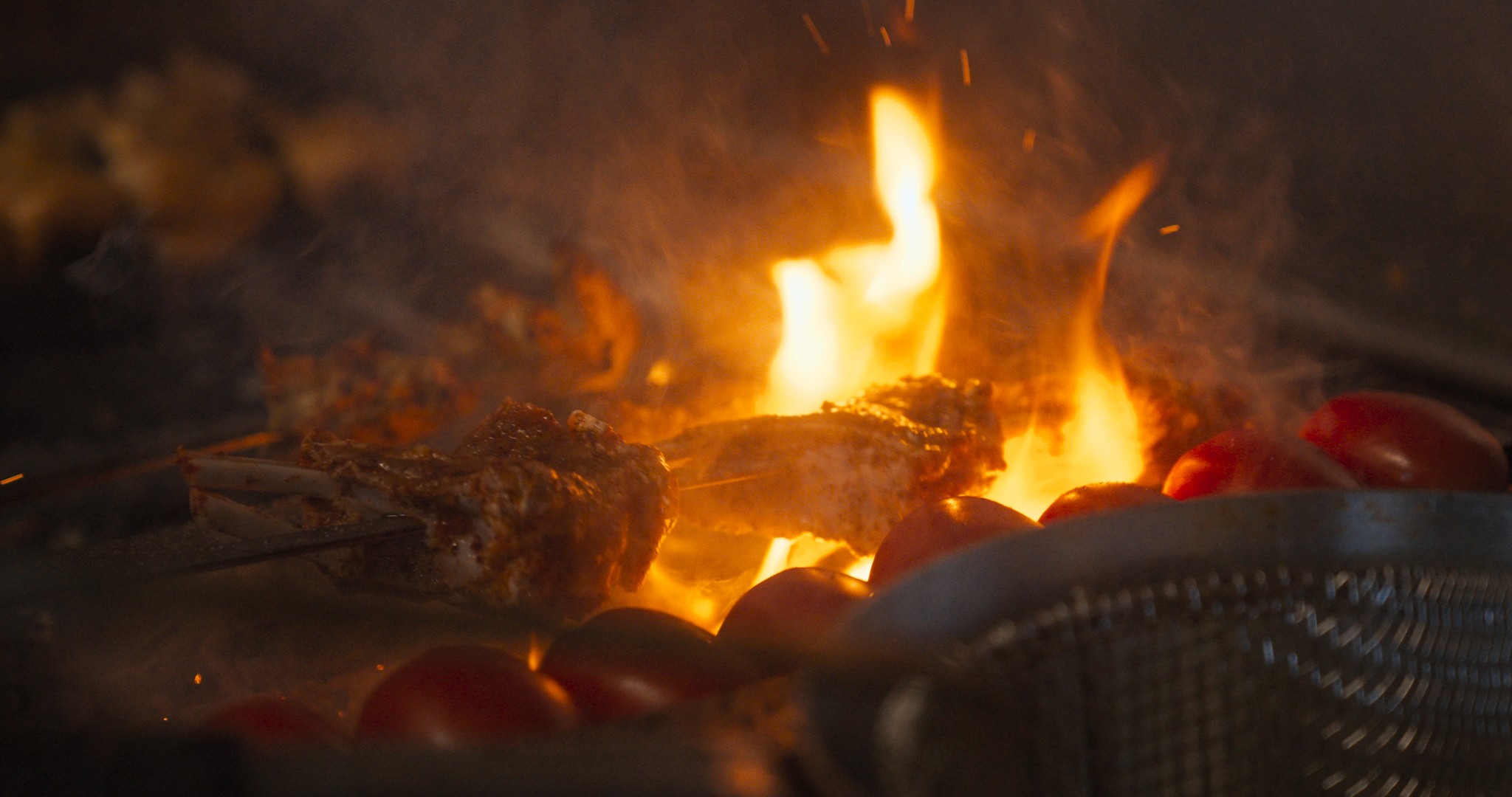 open grill and fire, lamb chops being grilled along with tomatos from Mini Kabob in Glendale California. 