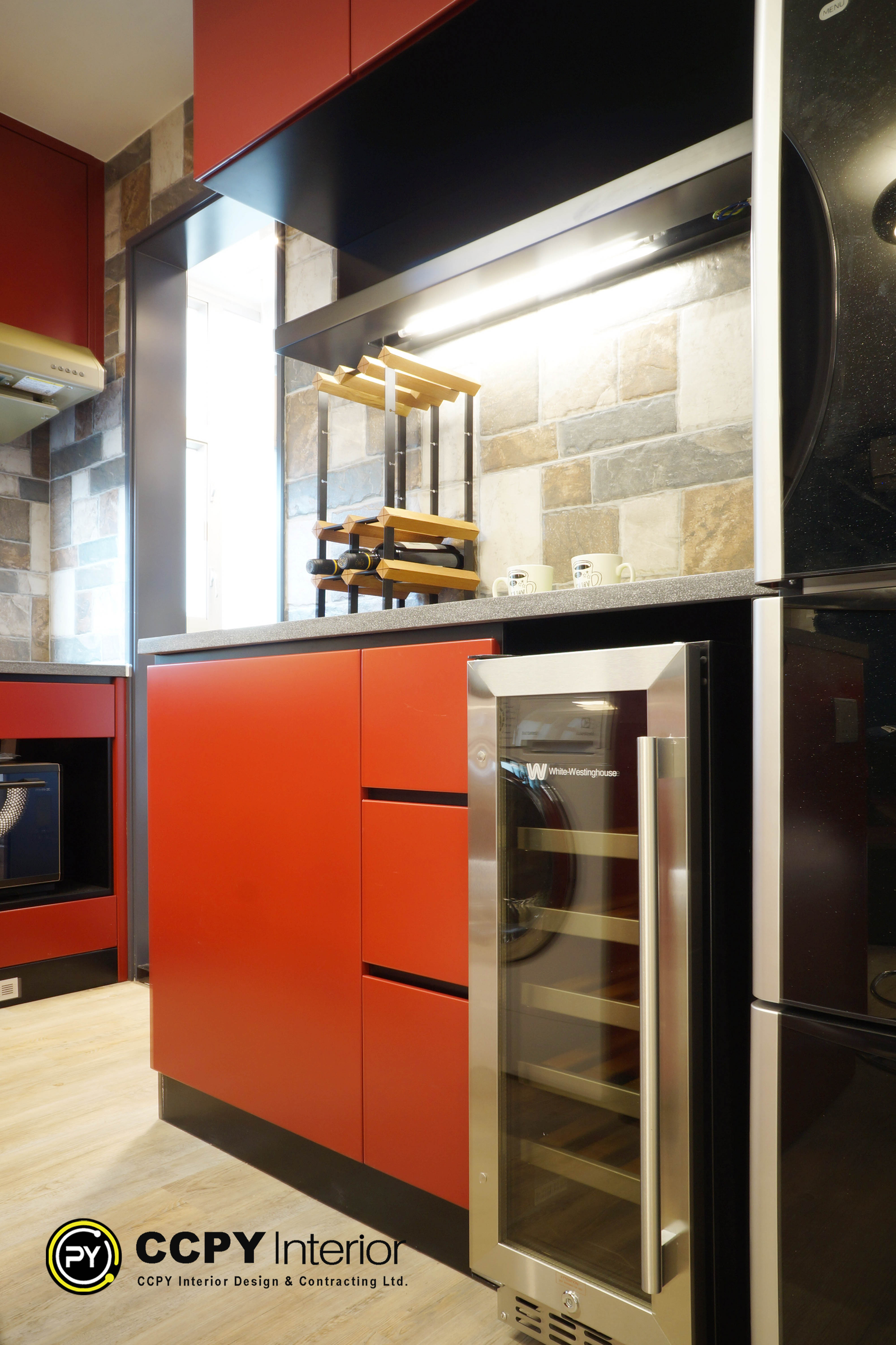 Cabinetry & Hardware: Features striking, custom high-gloss burnt orange and charcoal grey cabinetry designed with handle-less, integrated push-to-open mechanisms.Smart Storage: Features multi-tier sliding pull-out organizer drawers maximize tight corner gaps and narrower floor dimensions.Built-in Appliances: Fully integrates luxury built-in compact appliances, including a premium glass-door White-Westinghouse wine cooler refrigerator seamlessly framed inside the cabinetry columns.Premium Finishes: Complemented by a speckled quartz/stone countertop, rustic earth-toned mosaic stone backsplash tiles, and ambient under-cabinet LED track lighting strips.