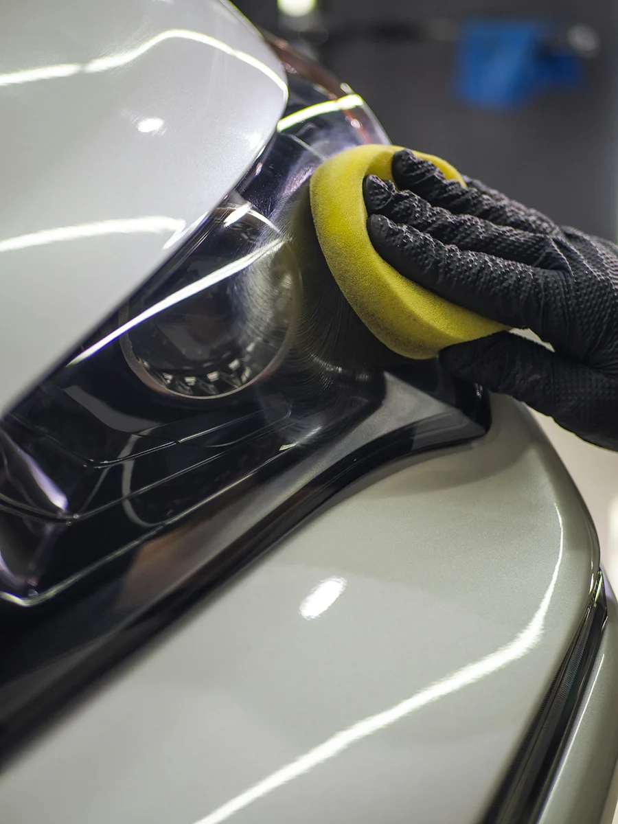 Detailer applying finishing polish to a vehicle body panel during paint correction service.