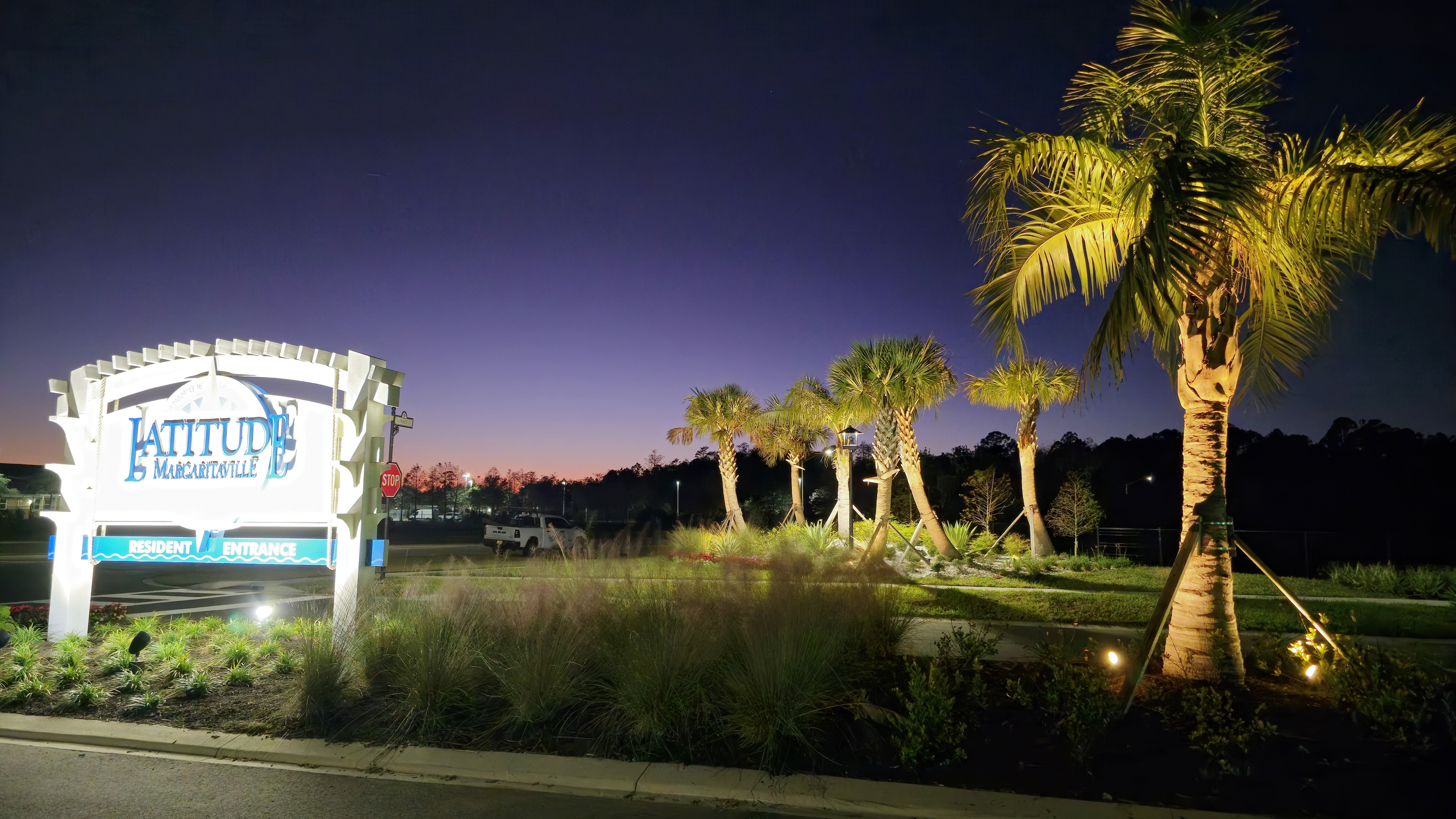 HOA community entrance lighting with illuminated signage and palm trees