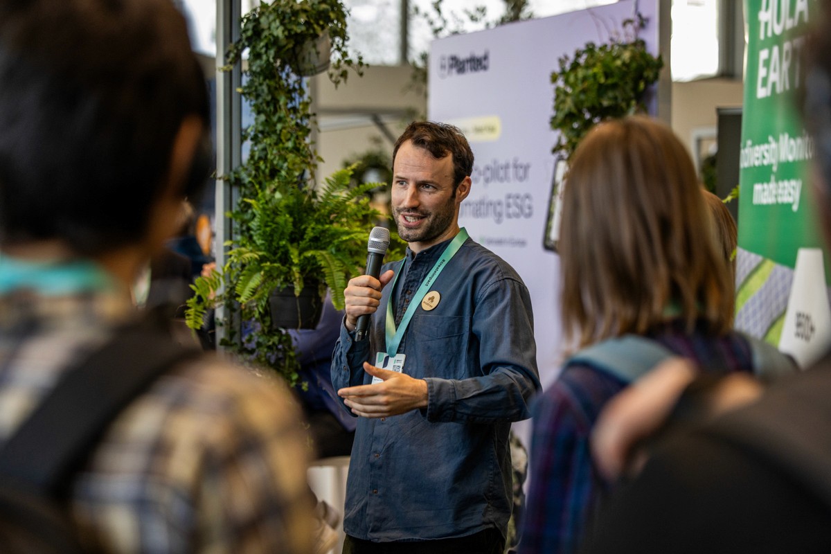 Drei Geschäftspersonen stehen an einem Tisch und blicken in die Kamera