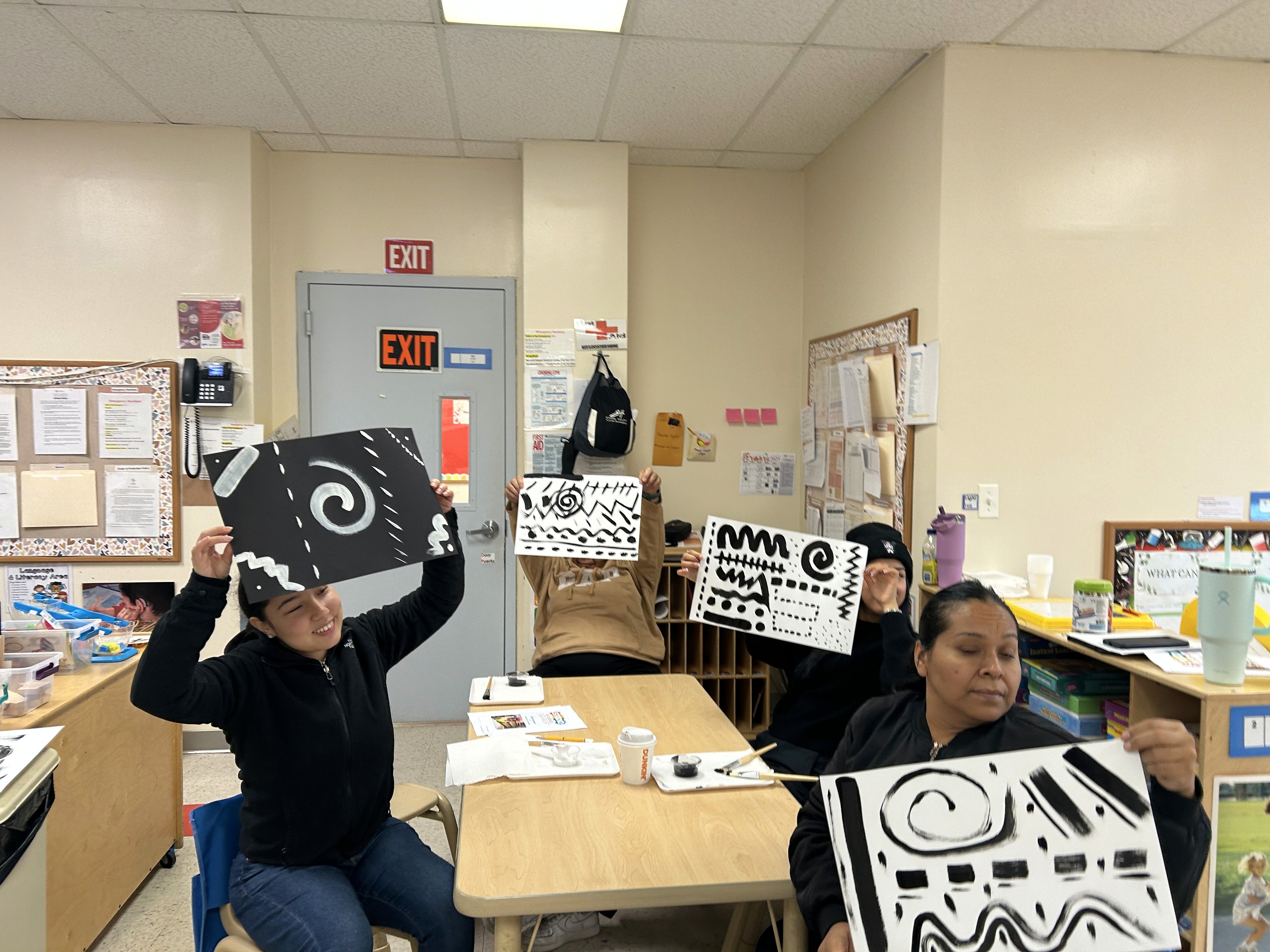 Teachers show off their abstract art pieces.