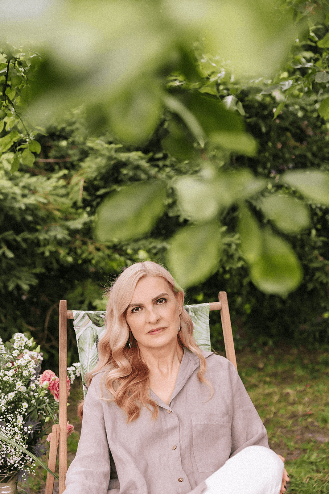 Beata Grala, psychoterapeutka, autorka warsztatów siedzi na krześle w ogrodzie.