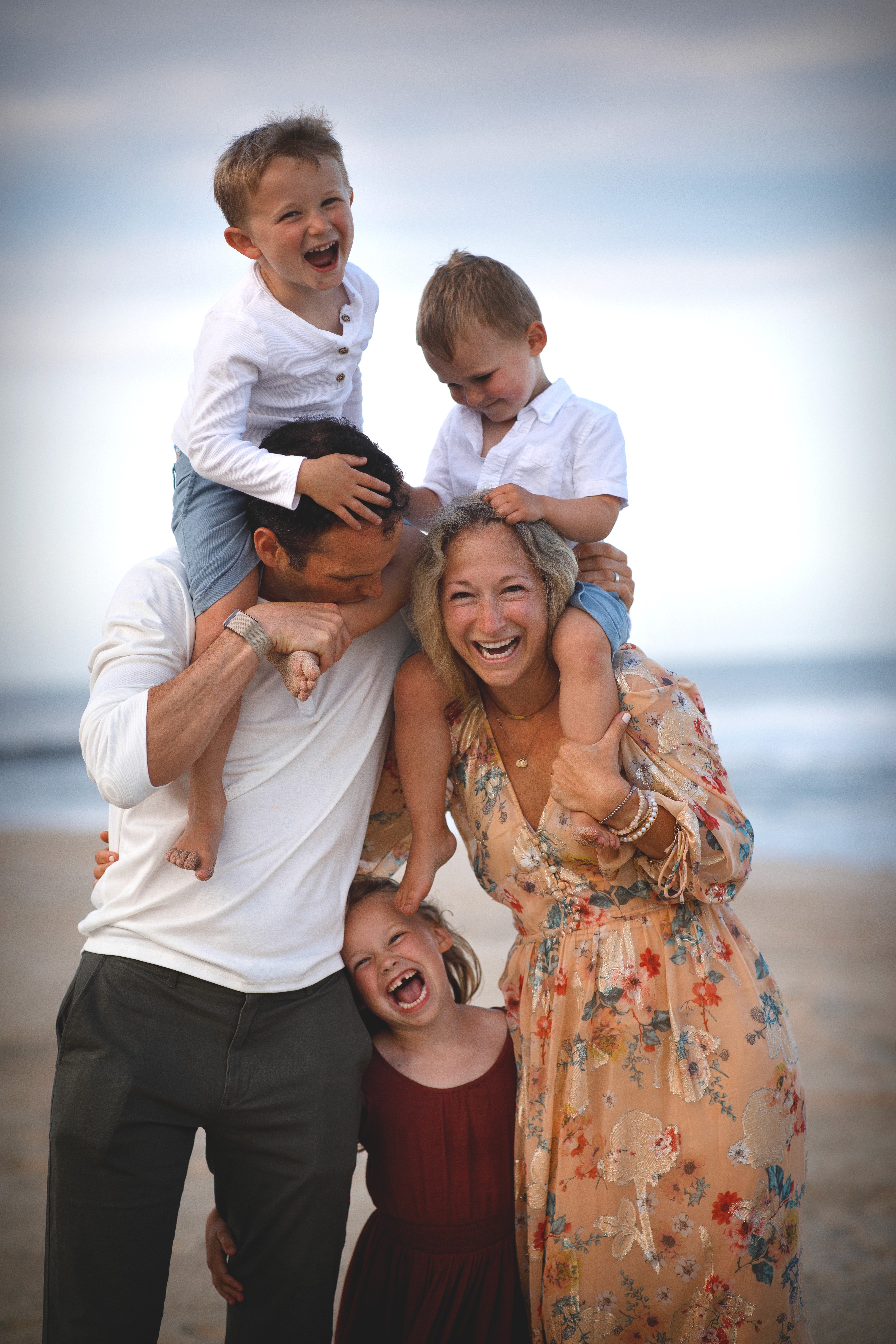 Dad carrying both kids on his shoulders while walking at the beach.