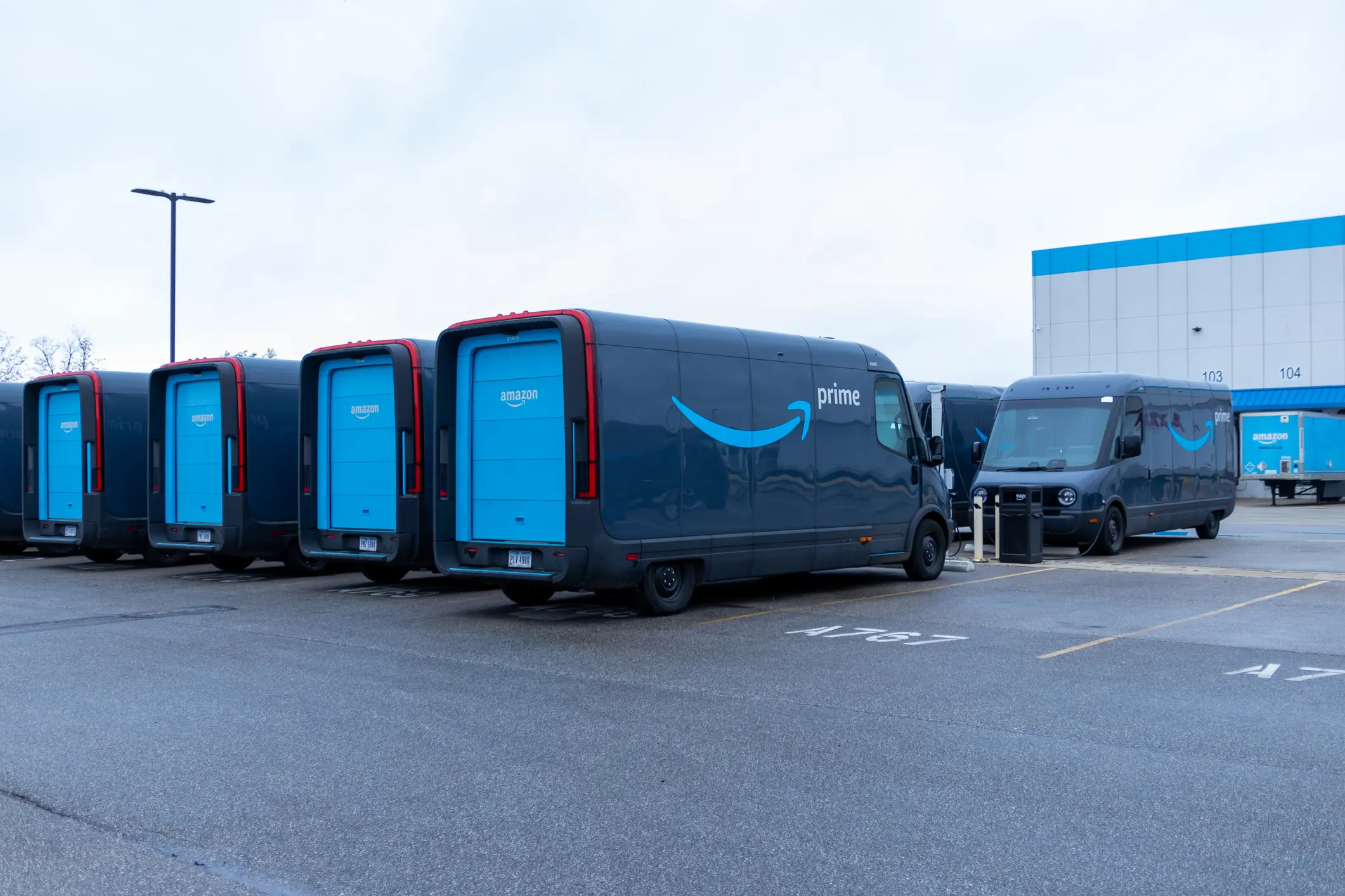 Amazon Prime delivery vans parked outside a distribution center — representing carrier compliance and registration steps for Amazon Relay onboarding.