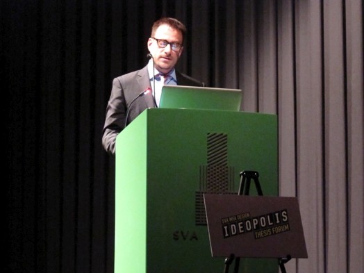 a man in a suit and tie is giving a speech from a green stand