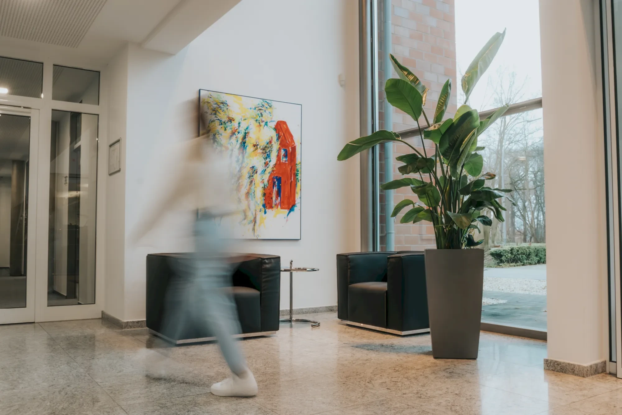 Moderner Eingangsbereich mit Kunst, Pflanzen und Sitzgelegenheiten. Büro- oder Hoteldesign.
