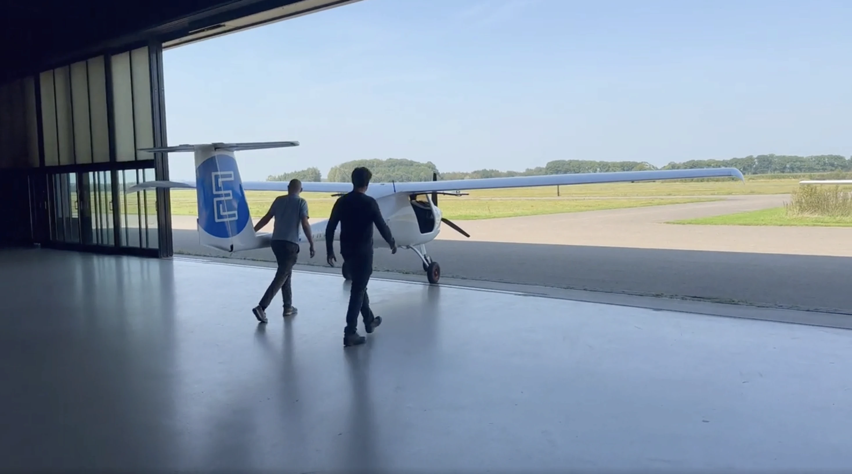 Elektrisch vliegtuig wordt handmatig uit de hangar geduwd voor een proefvlucht.