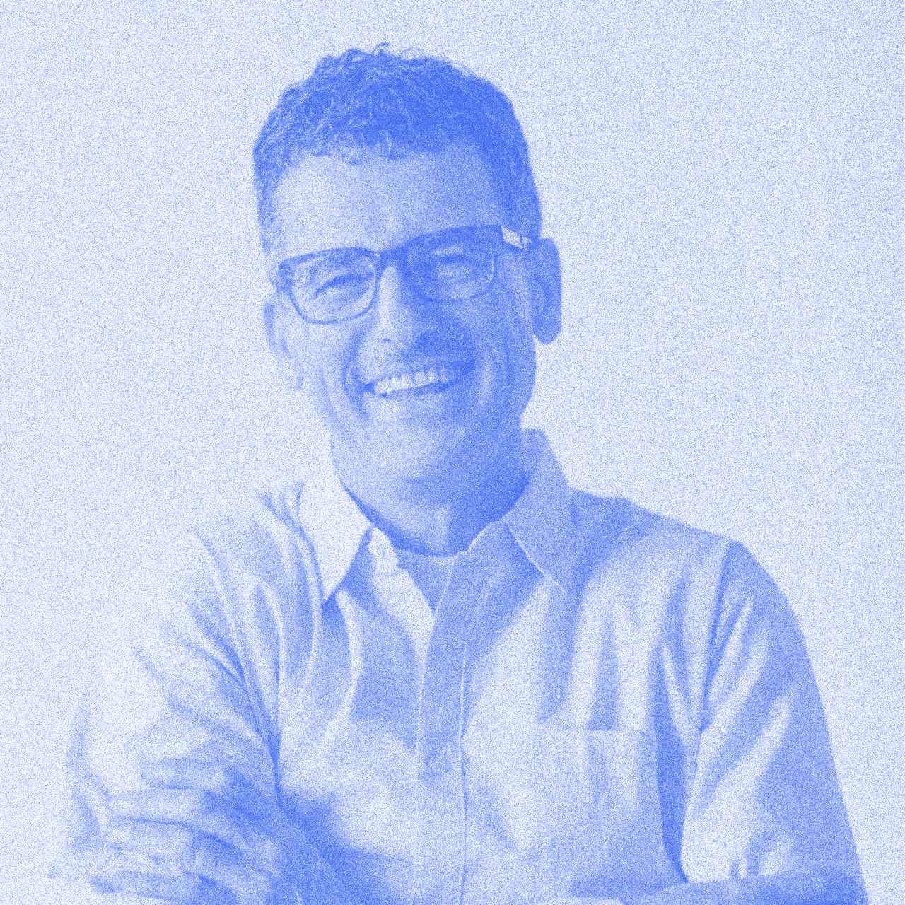 Man smiling in blue filter. Shirt with letters.