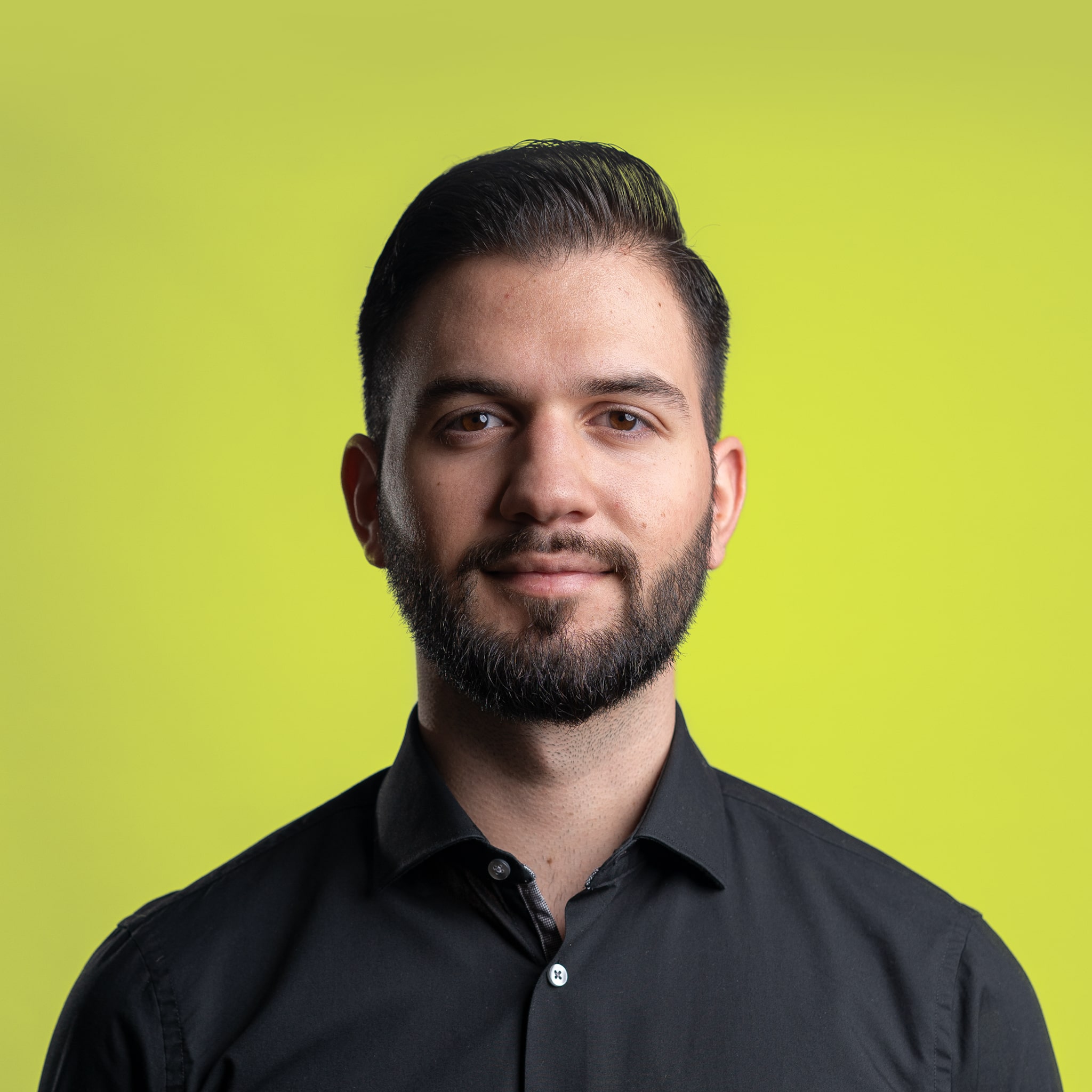 A young person with long, wavy hair sits in front of a plain background, looking directly at the camera.