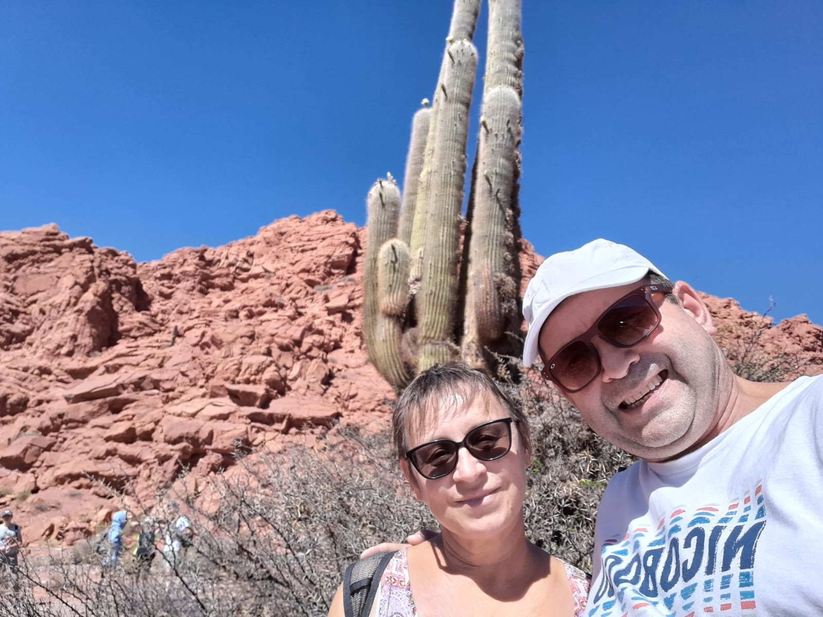 Mujer sentada sobre un tronco frente a una cascada doble en un bosque frondoso de Argentina.