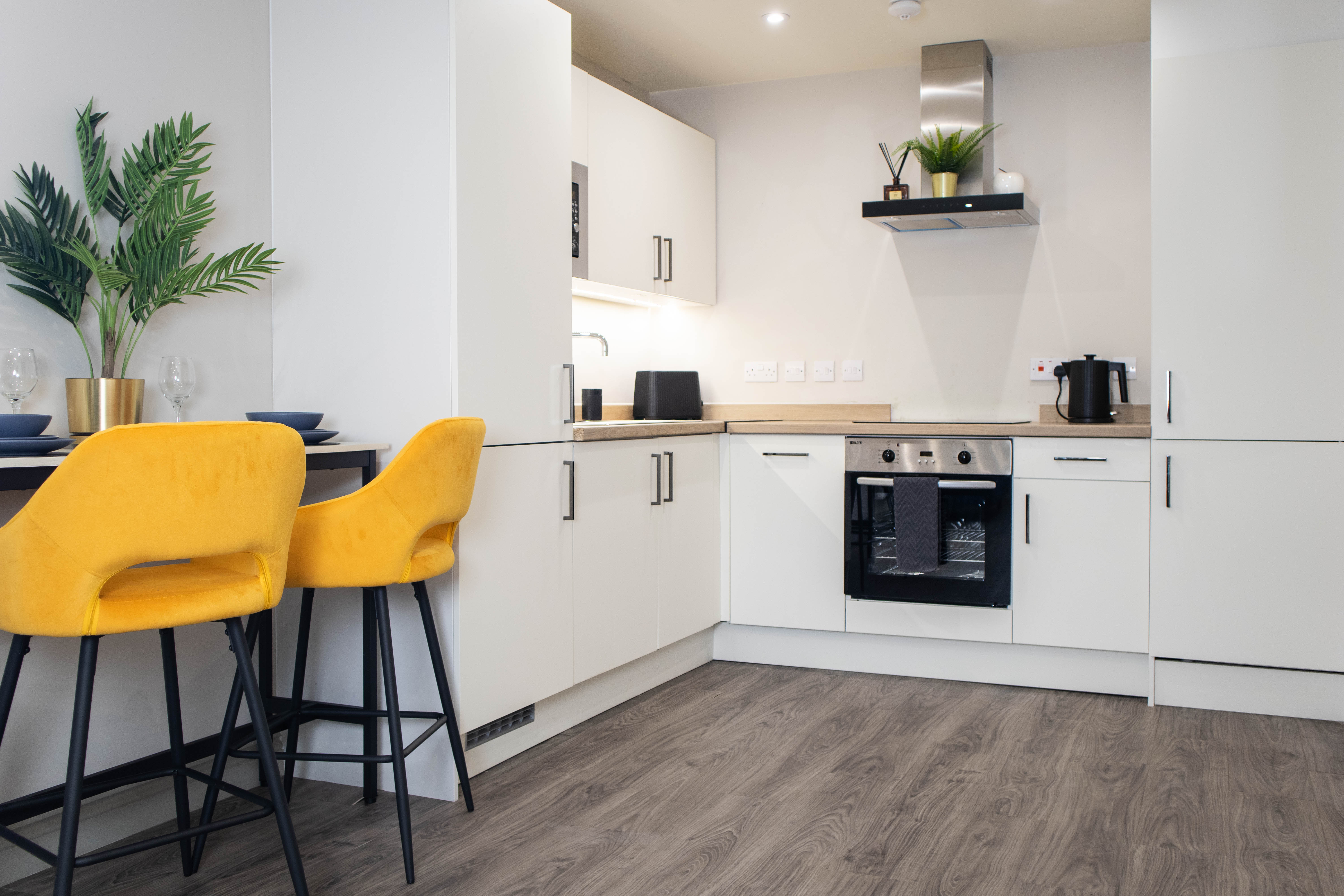Open plan bright modern Airbnb kitchen with breakfast bar and yellow chairs