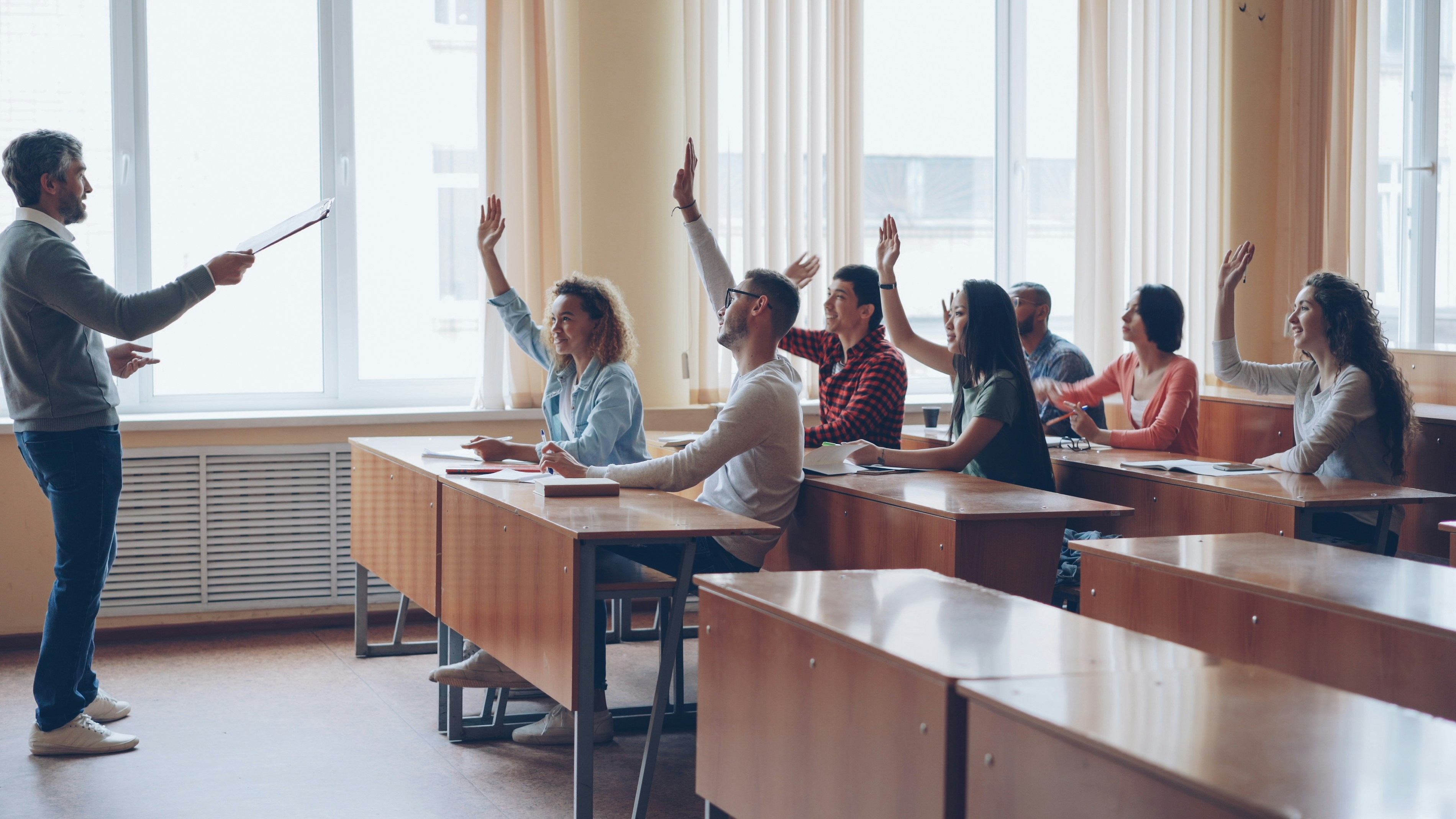 Teacher pointing at students with raised hands