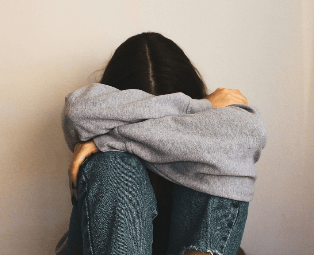 Young person sitting on the floor with their head in their arms