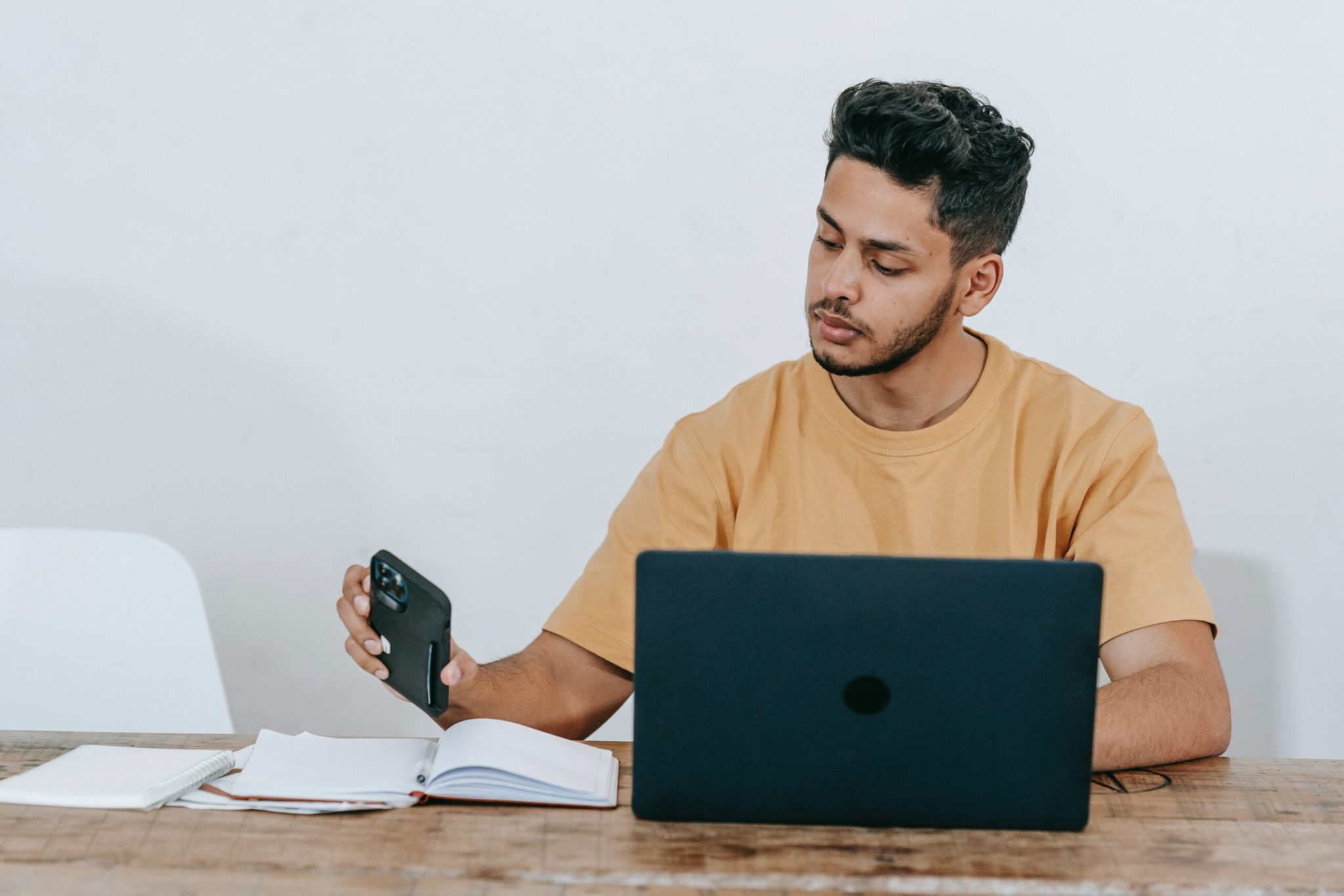 Man working at laptop while holding smartphone