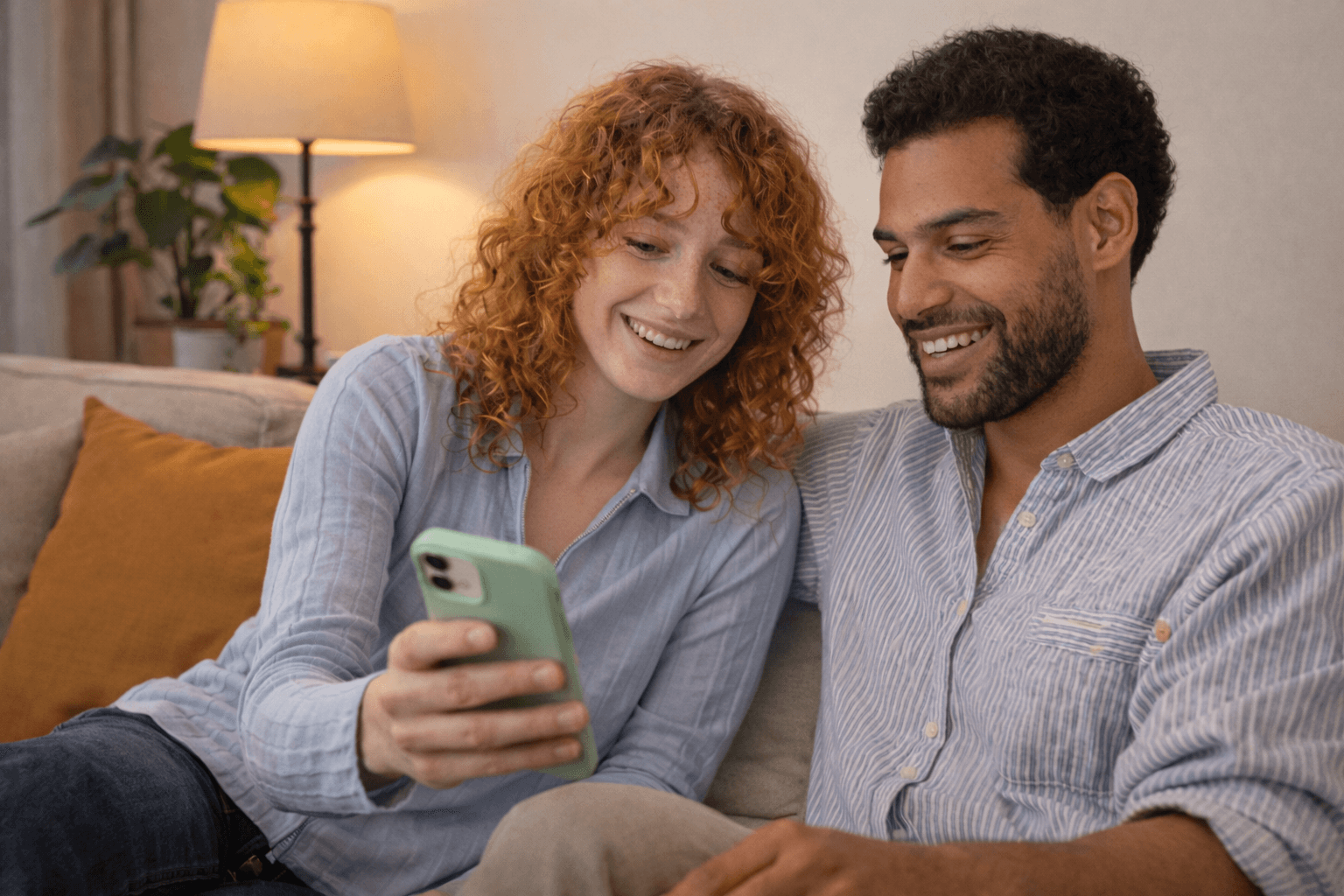 woman holding a phone and man looking at the phone. both are smiling
