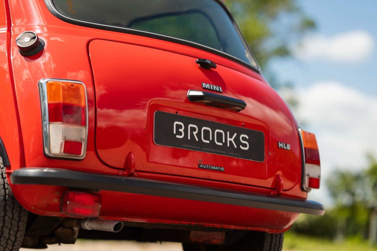 A close-up of the rear of a bright red car, featuring its taillight and license plate that reads "ORIGINALS."