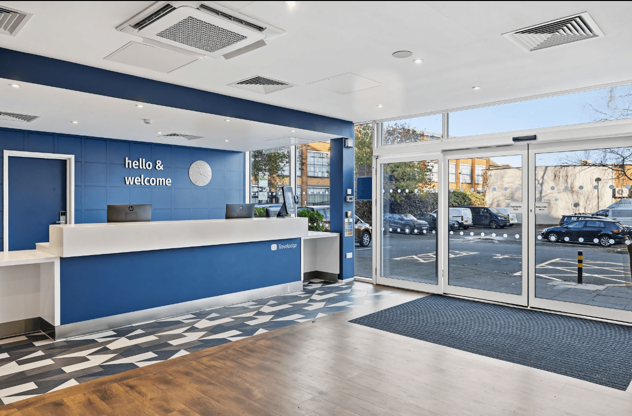 A winding road cuts through rocky terrain, surrounded by patches of green grass and illuminated by sunlight.