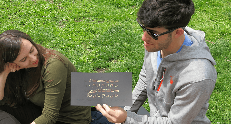 A photo of a woman and man that is holding a black card with some gold text on it.