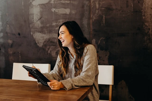 Woman smiling while working on a laptop at a desk, symbolizing tracking health habits and measurable progress.