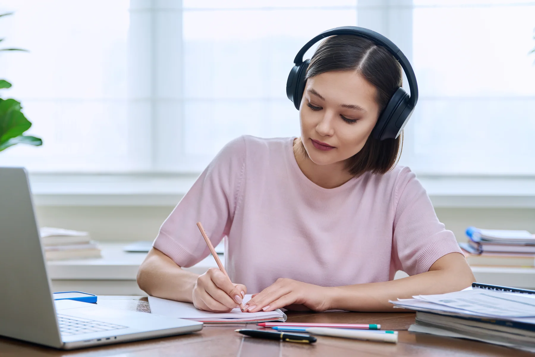 Woman Studying and Writing at Desk with Laptop