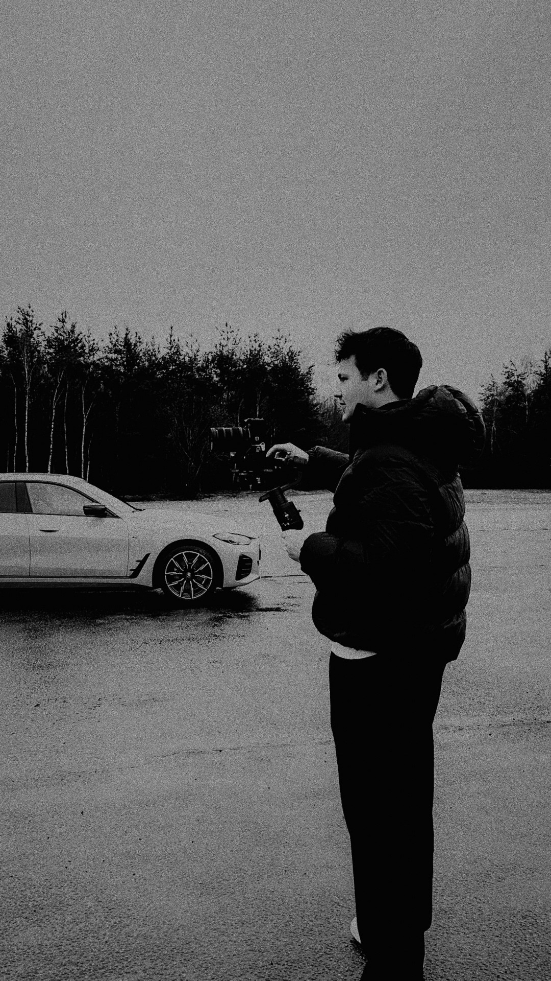 Felix Greppmair holding a gimbal and camera pointing at a gray car on the left side of the frame
