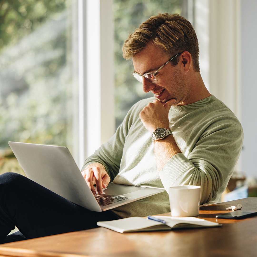 Man working on laptop at table with a garden view