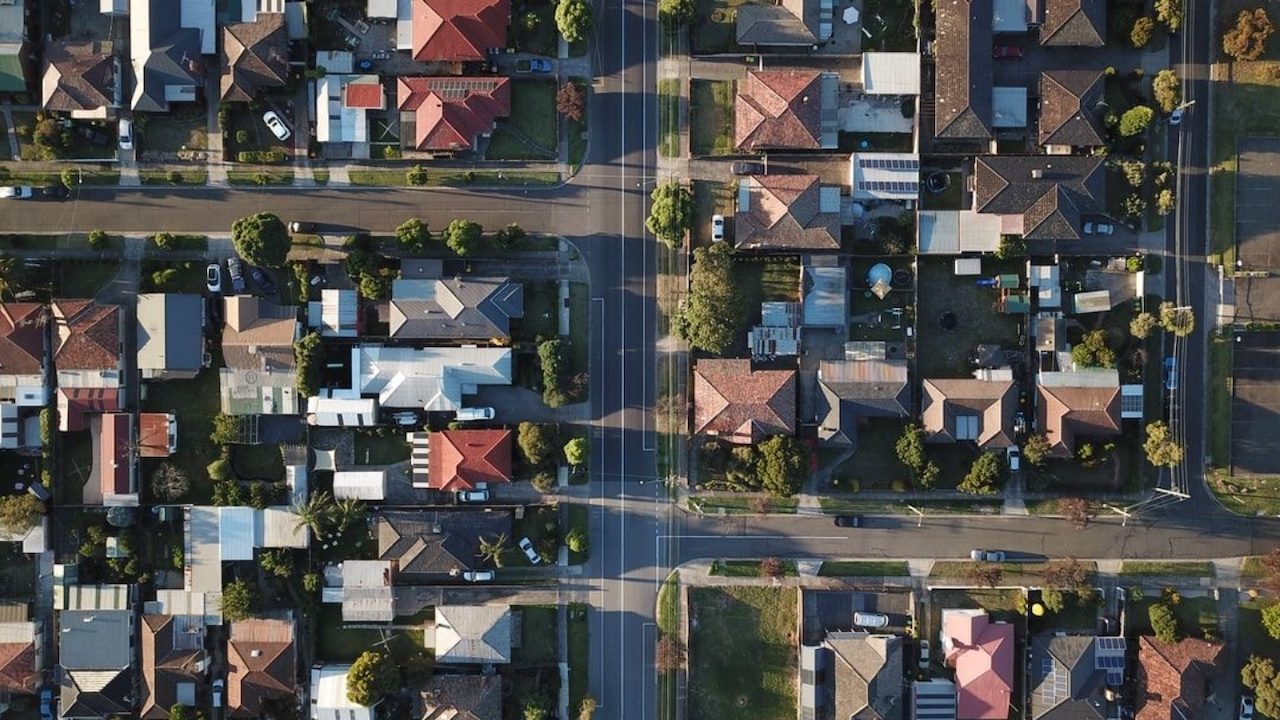 Overhead view of suburban rooftops and streets.